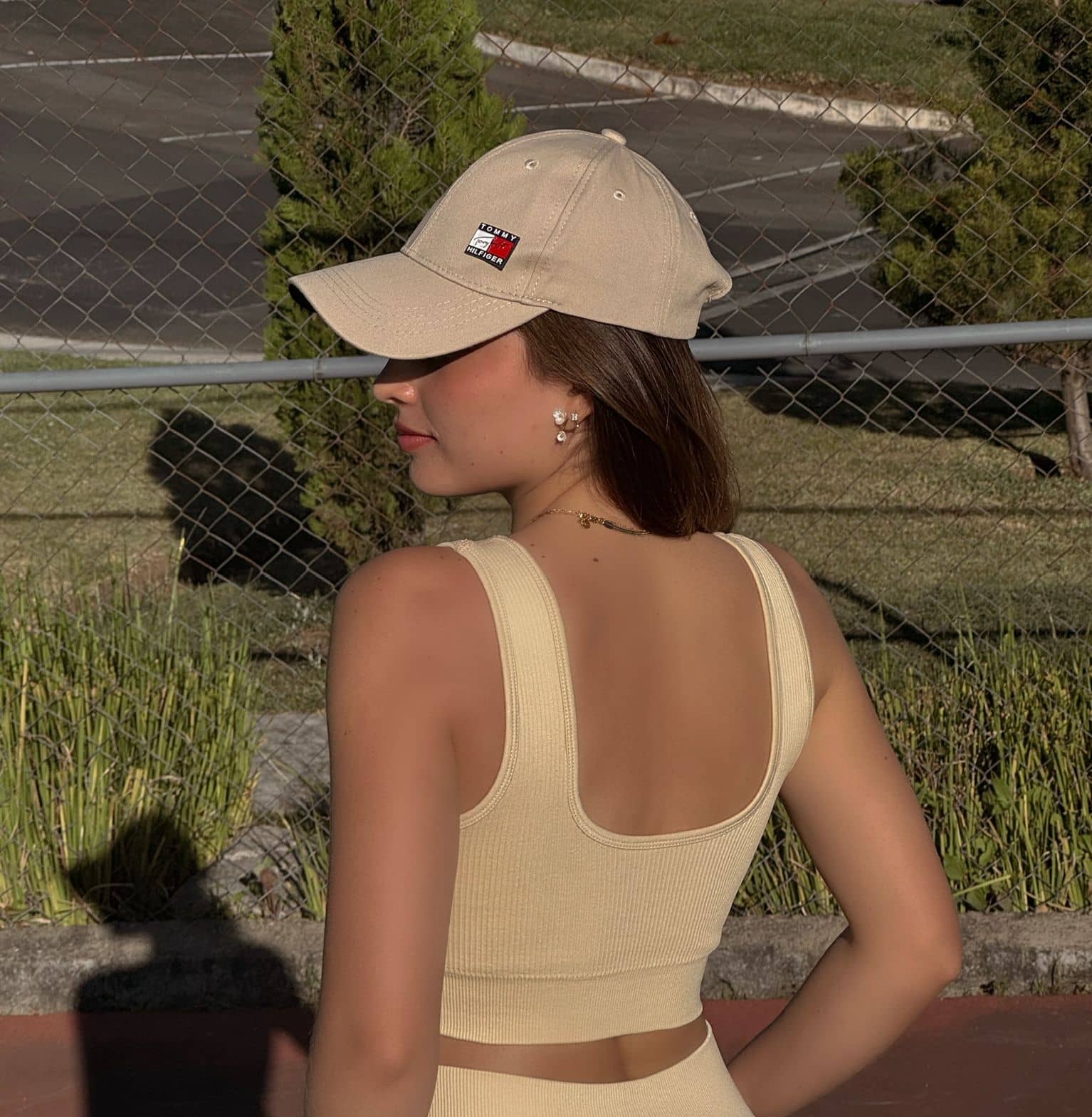 Vista posterior de un top de activewear color butter yellow sin mangas, mostrando el ajuste y diseño minimalista en una cancha deportiva.